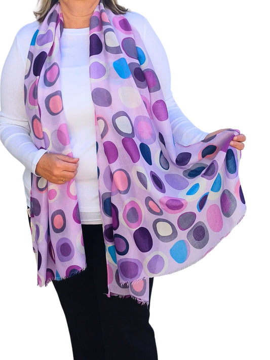 Light purple scarf with a retro oval and circle pattern in shades of purple, pink, and blue. Soft, flowing fabric with fringed ends.