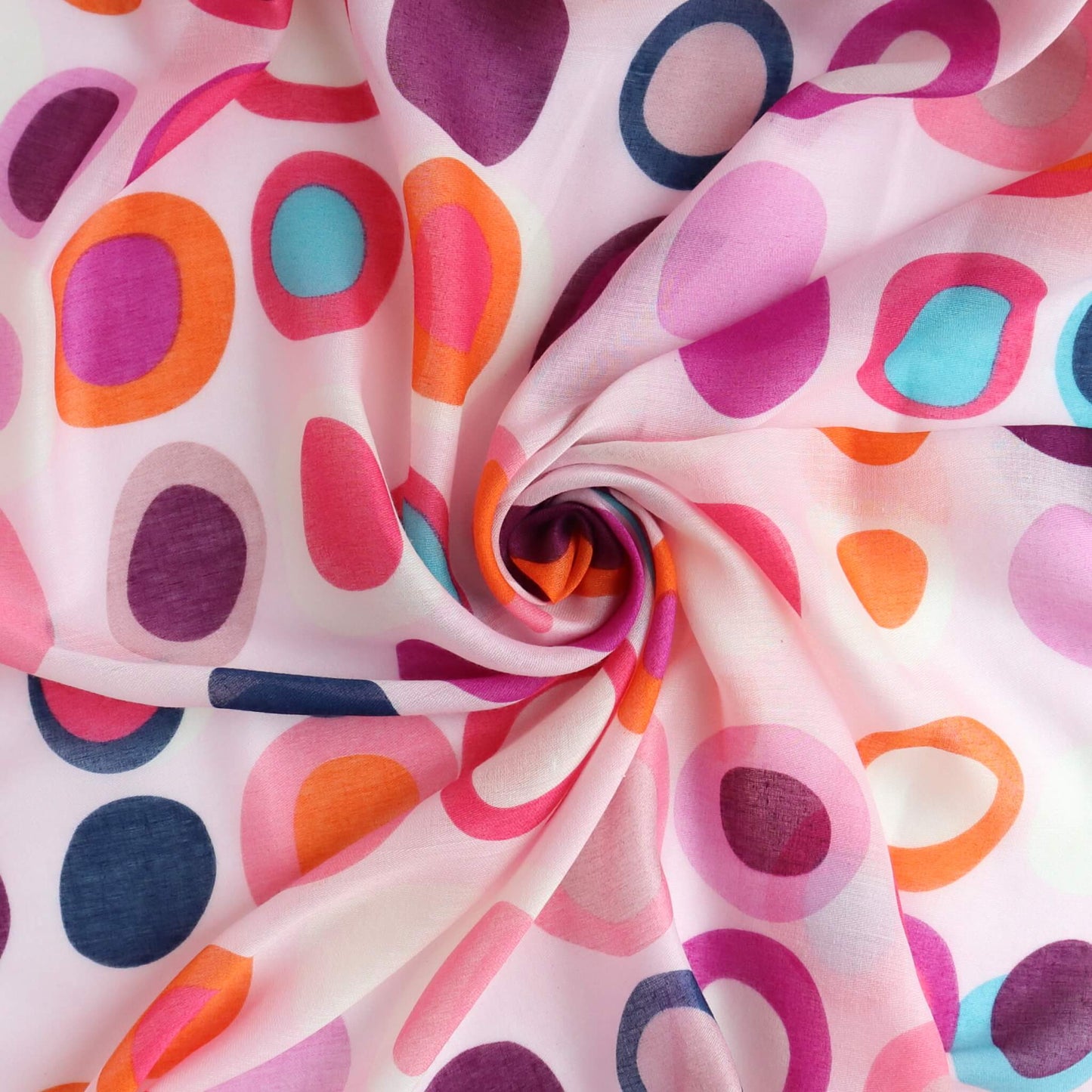 Pale pink scarf fabric with a vibrant retro circle and oval design in fuchsia, orange, purple, and blue. Lightweight, flowing textile with a central swirl.