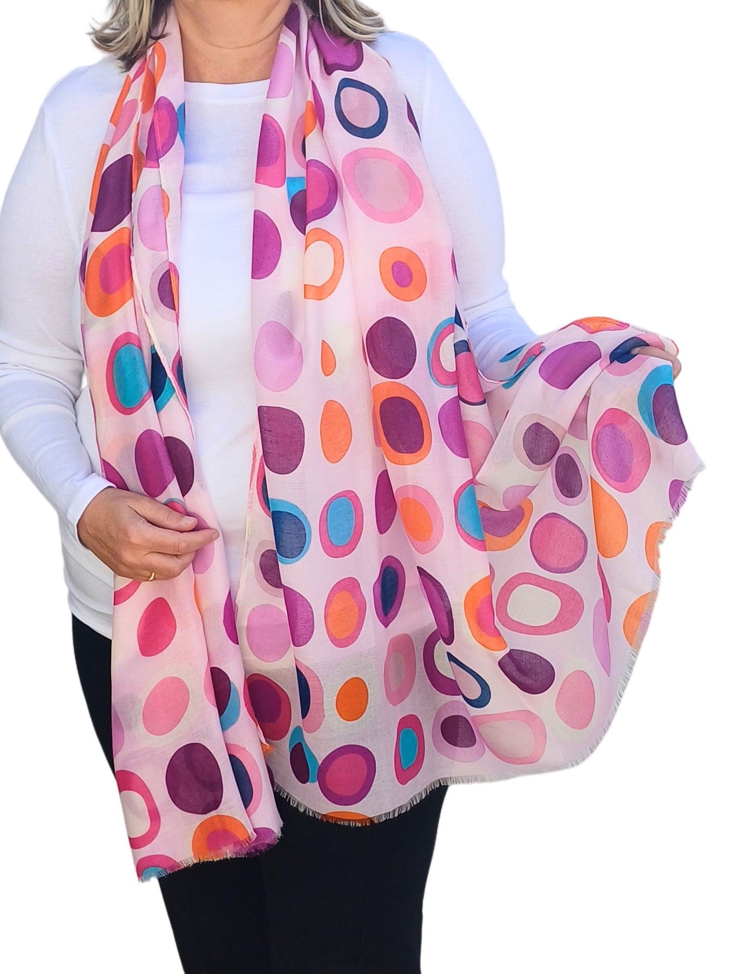 Pale pink scarf featuring a retro-inspired circle and oval design in shades of pink, purple, orange, and blue. Soft, lightweight material with fringed edges.