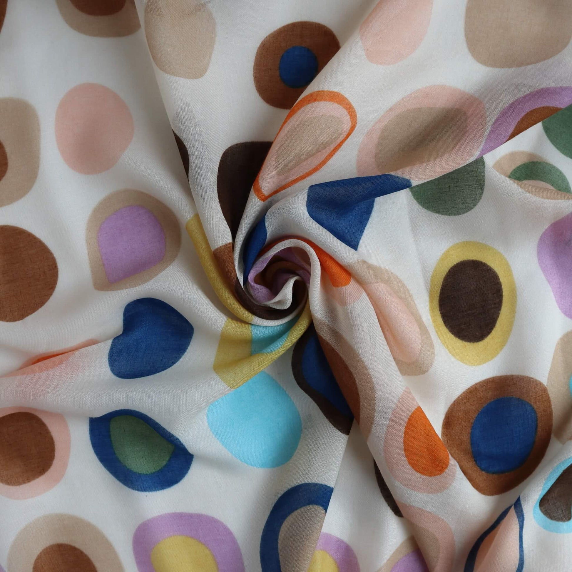Beige scarf fabric with a playful circle and oval design in brown, blue, pink, lilac, and yellow. Light, flowing textile with a central swirl.