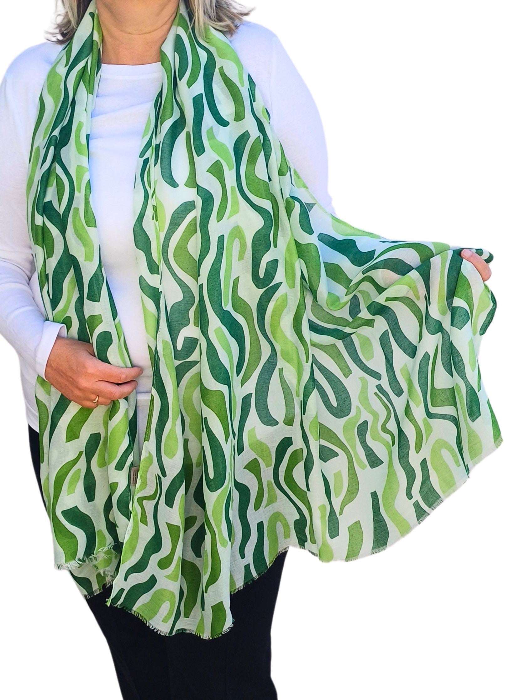 Aurora's Array: Woman models a soft, lightweight oversized scarf with an abstract wavy stripe print in shades of green and white.