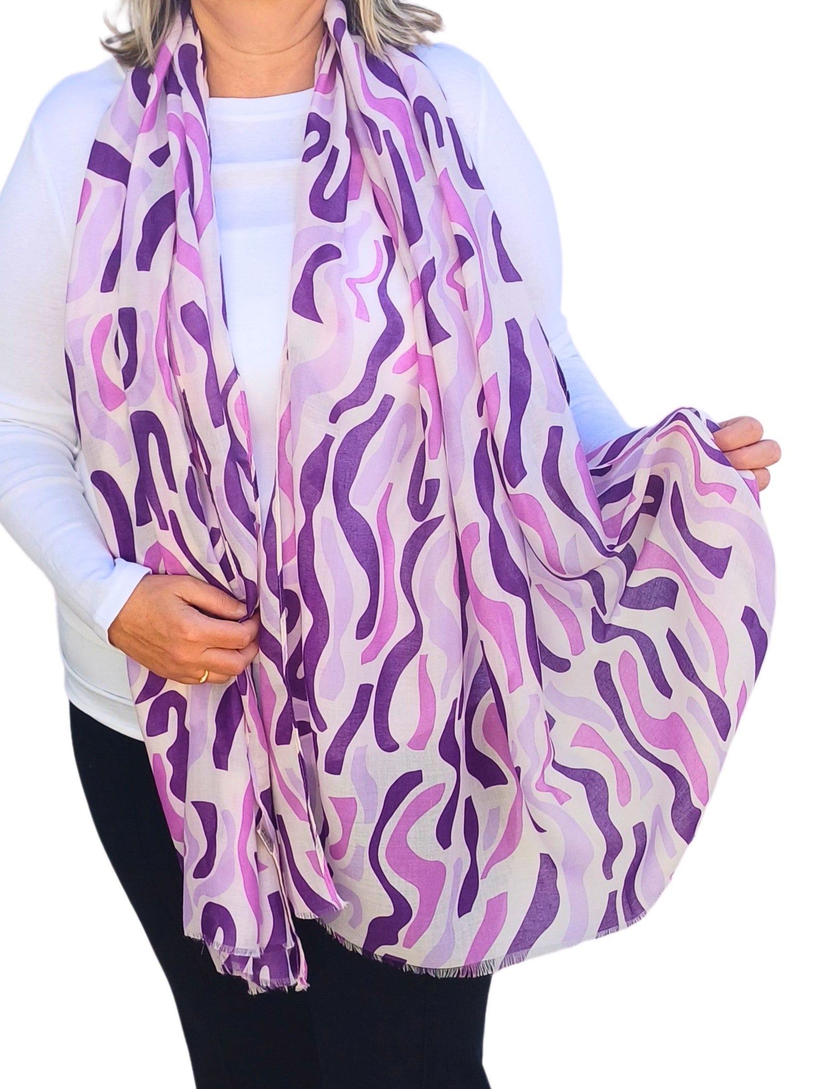 Aurora's Array: Woman models a soft, lightweight oversized scarf with an abstract wavy stripe print in shades of purple and white.