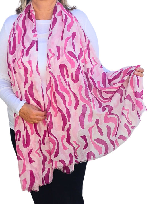 Aurora's Array: Woman models a soft, lightweight oversized scarf with an abstract wavy stripe print in shades of pink and white.