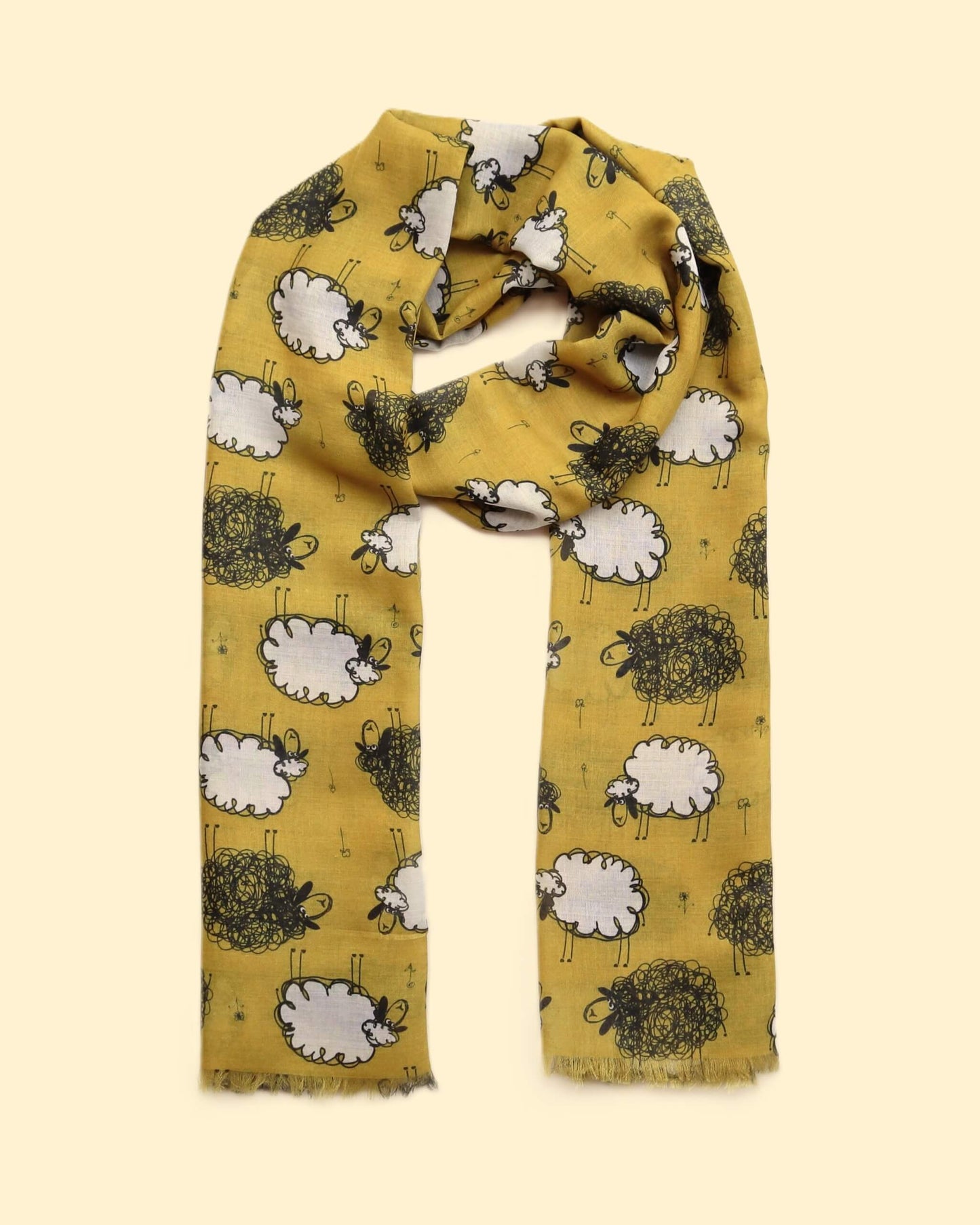 Golden mustard scarf decorated with a playful array of black and white sheep. Lightweight fabric with a soft drape and subtle fringed ends.