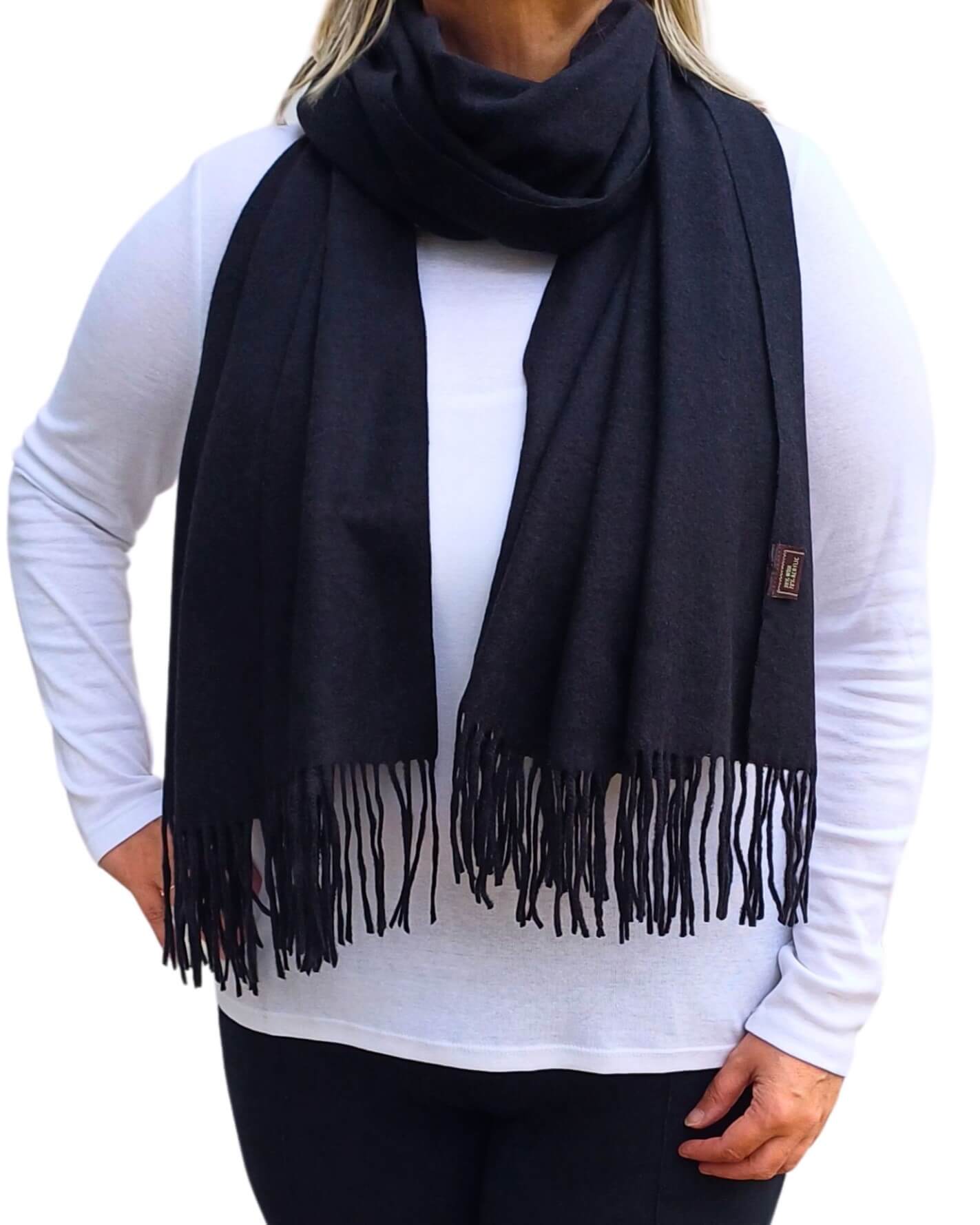 Aurora's Array: Woman models a soft, warm black wool blend scarf with fringed edges, draped around her neck and shoulders.