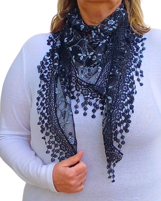 Aurora's Array Glitter Triangle Scarf with Lace & Embroidery: A woman models a dark navy blue, sheer triangle scarf with a delicate white floral print, intricate lace trim, and dangling embroidered accents.