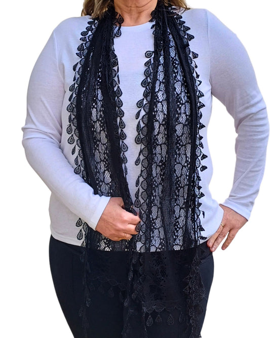 Aurora's Array: Woman models a sophisticated black lace scarf with a delicate leaf-like pattern and fringed edges.