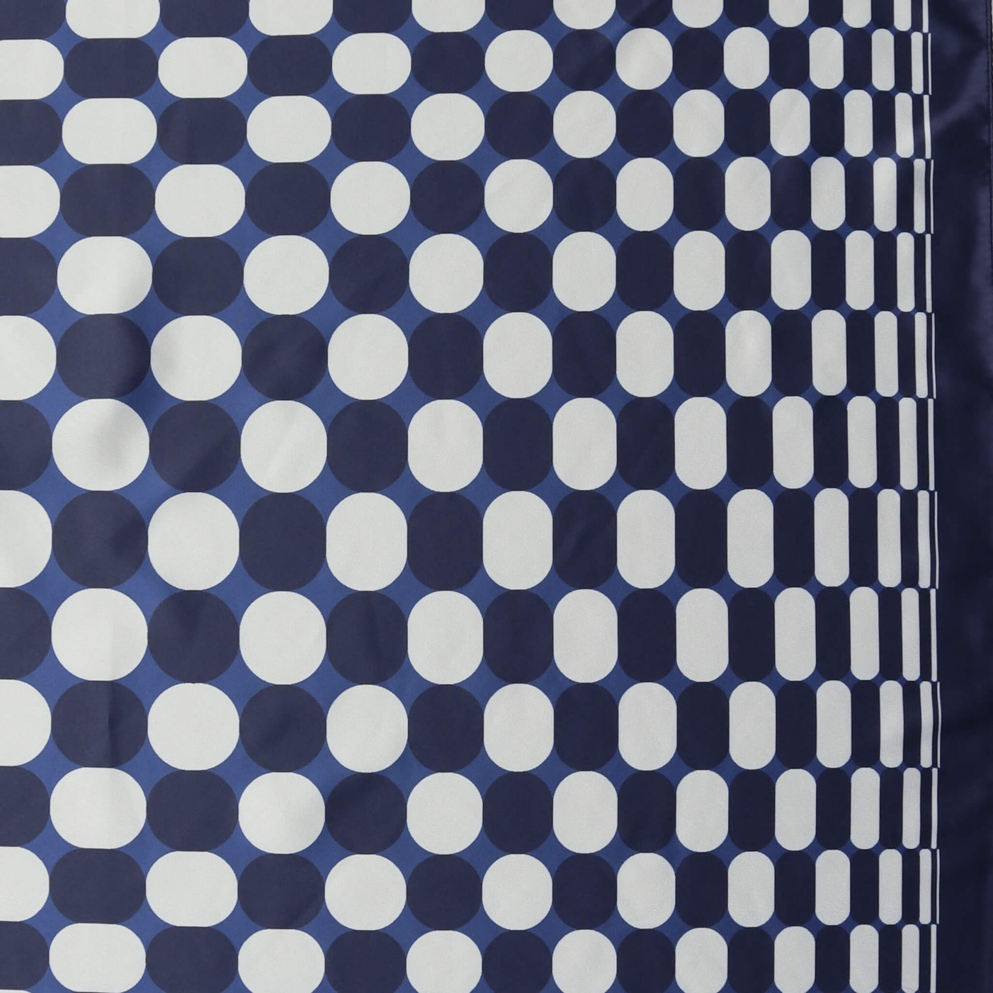 Aurora's Array: Close-up of a small square satin scarf with a geometric pattern of white dots on a navy blue background, featuring a border design of clustered white dots on the right edge.