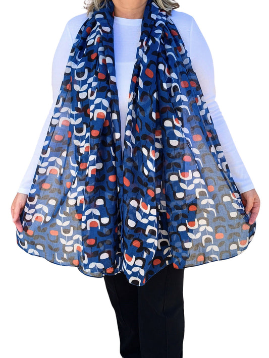 Aurora's Array:  Woman models a soft, lightweight oversized scarf with a retro floral print in shades of blue, white, orange, and black.