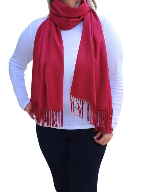 Bright berry red medium weight pashmina scarf with tassels, shown styled loosely around the neck.