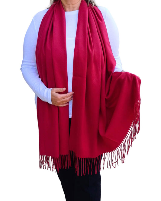 Bright berry red pashmina scarf with tassels, shown draped over the shoulders in a medium weight wrap style.