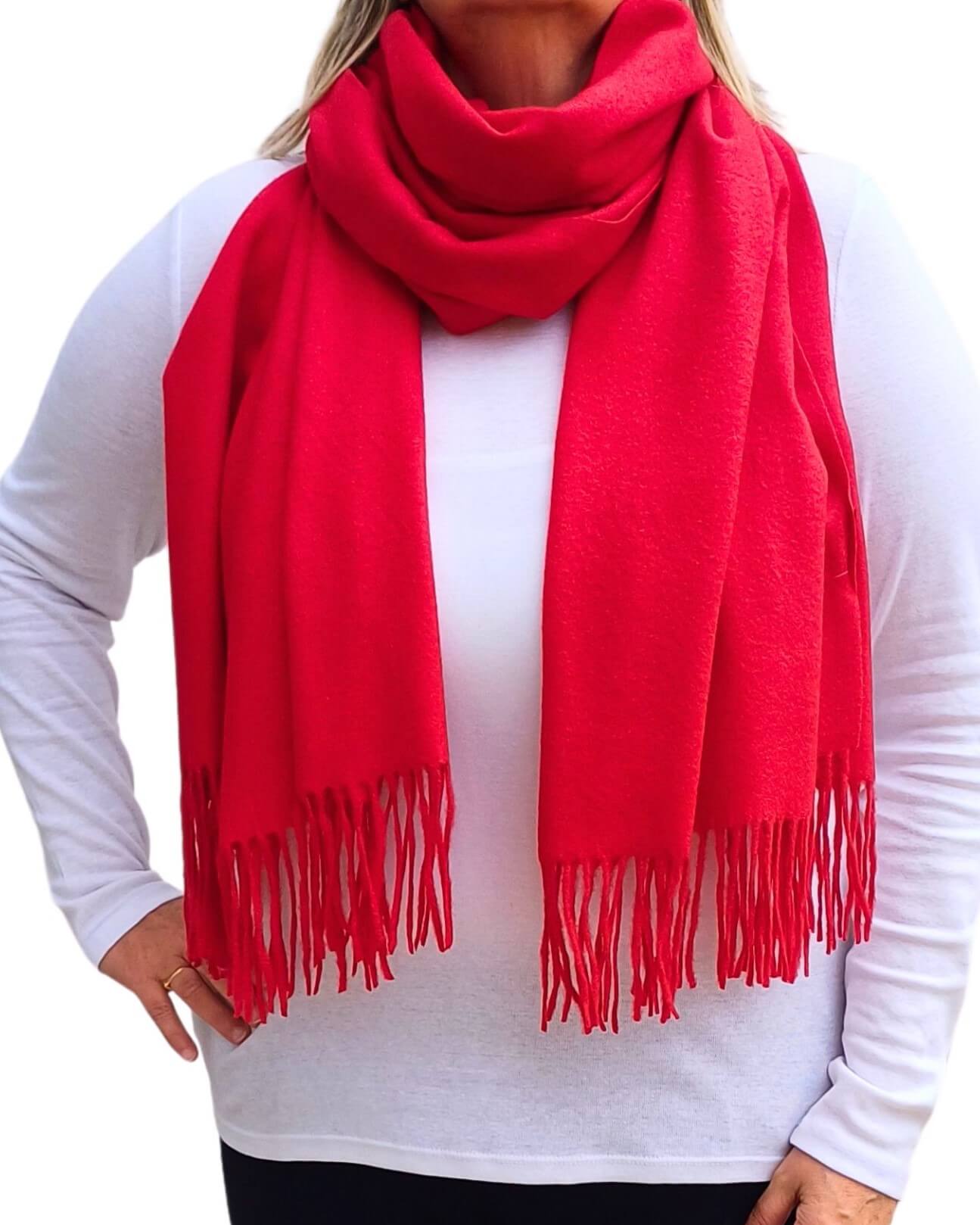 Aurora's Array: Woman models a soft, warm bright red wool blend scarf with fringed edges, draped around her neck and shoulders.