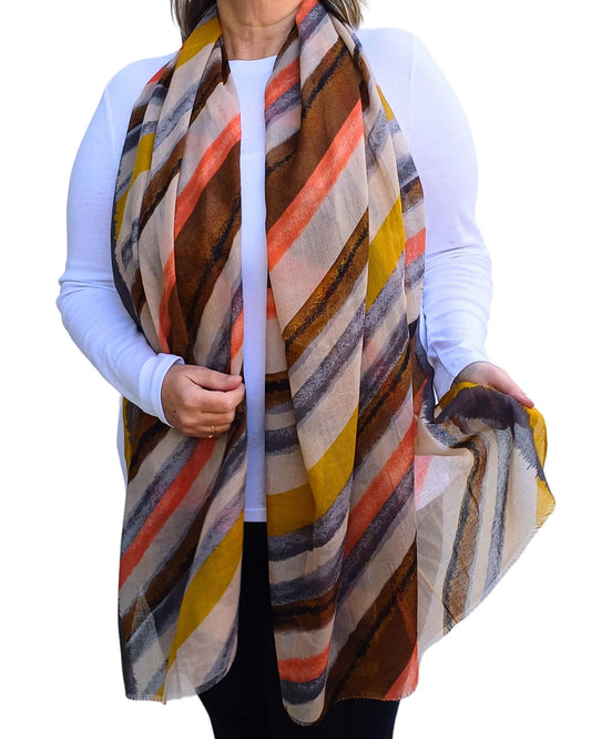 Aurora's Array: Woman models a soft, lightweight oversized scarf with diagonal stripes in mustard yellow, orange, brown, grey, and cream.