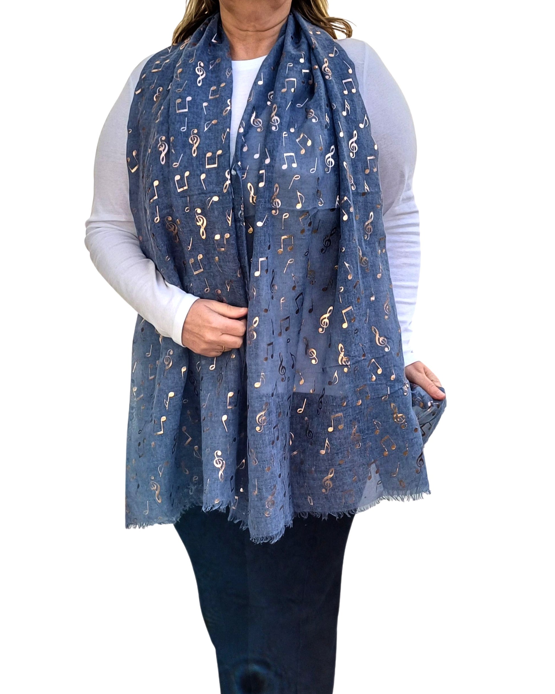 Aurora's Array: Muted denim blue scarf with a metallic gold musical note pattern draped around a person wearing a white top and dark trousers.