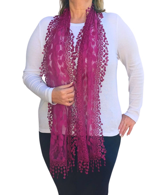 Aurora's Array: Woman models a rich fuchsia pink lace scarf with a delicate leaf pattern and fringed edges.