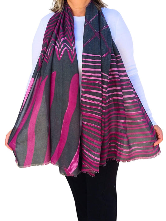 Aurora's Array: Woman models a soft, lightweight oversized scarf with a grey and fuchsia pink geometric print and frayed edges.