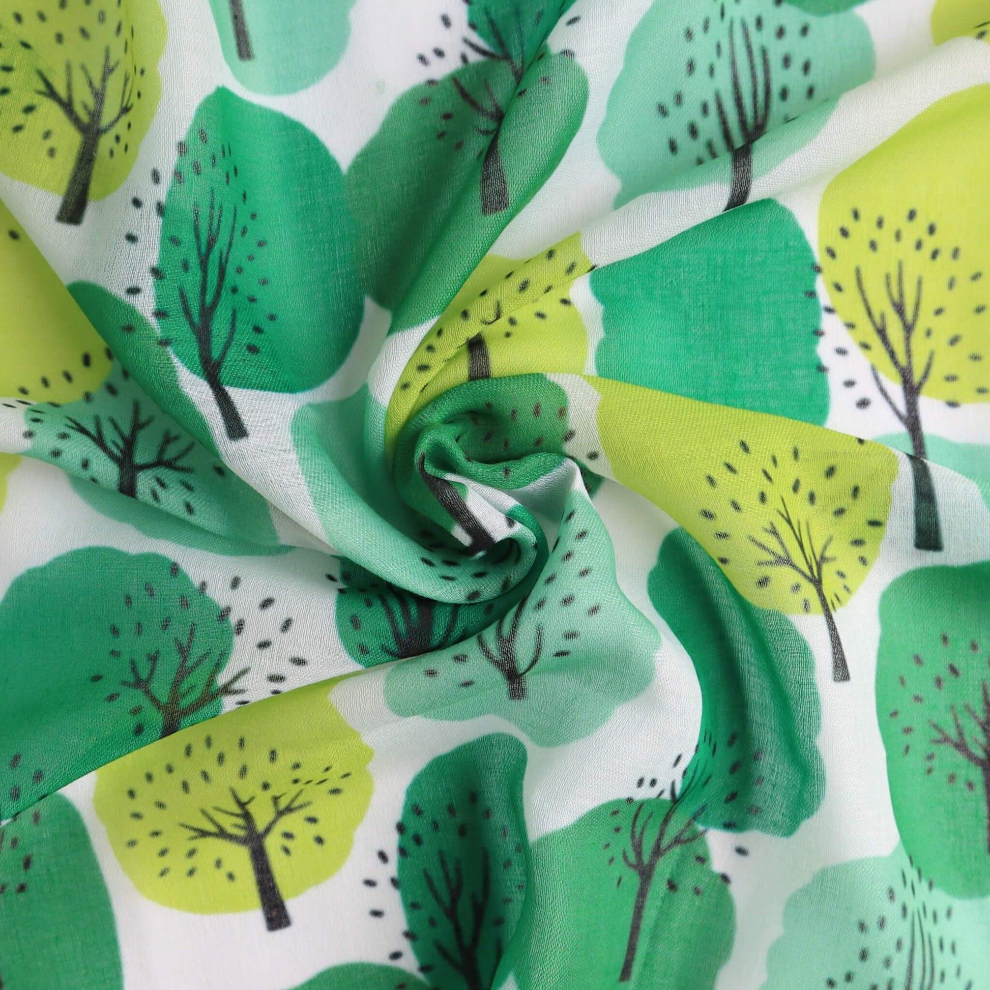 White scarf fabric with an abstract tree pattern in shades of light and dark green, and lime yellow. Sheer, flowing textile with a central swirl.
