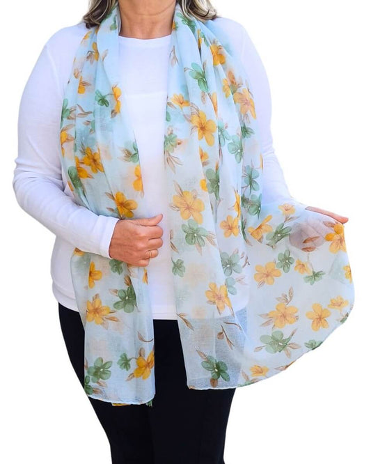 Aurora's Array: Woman models a soft, lightweight light scarf with a yellow and green floral print.