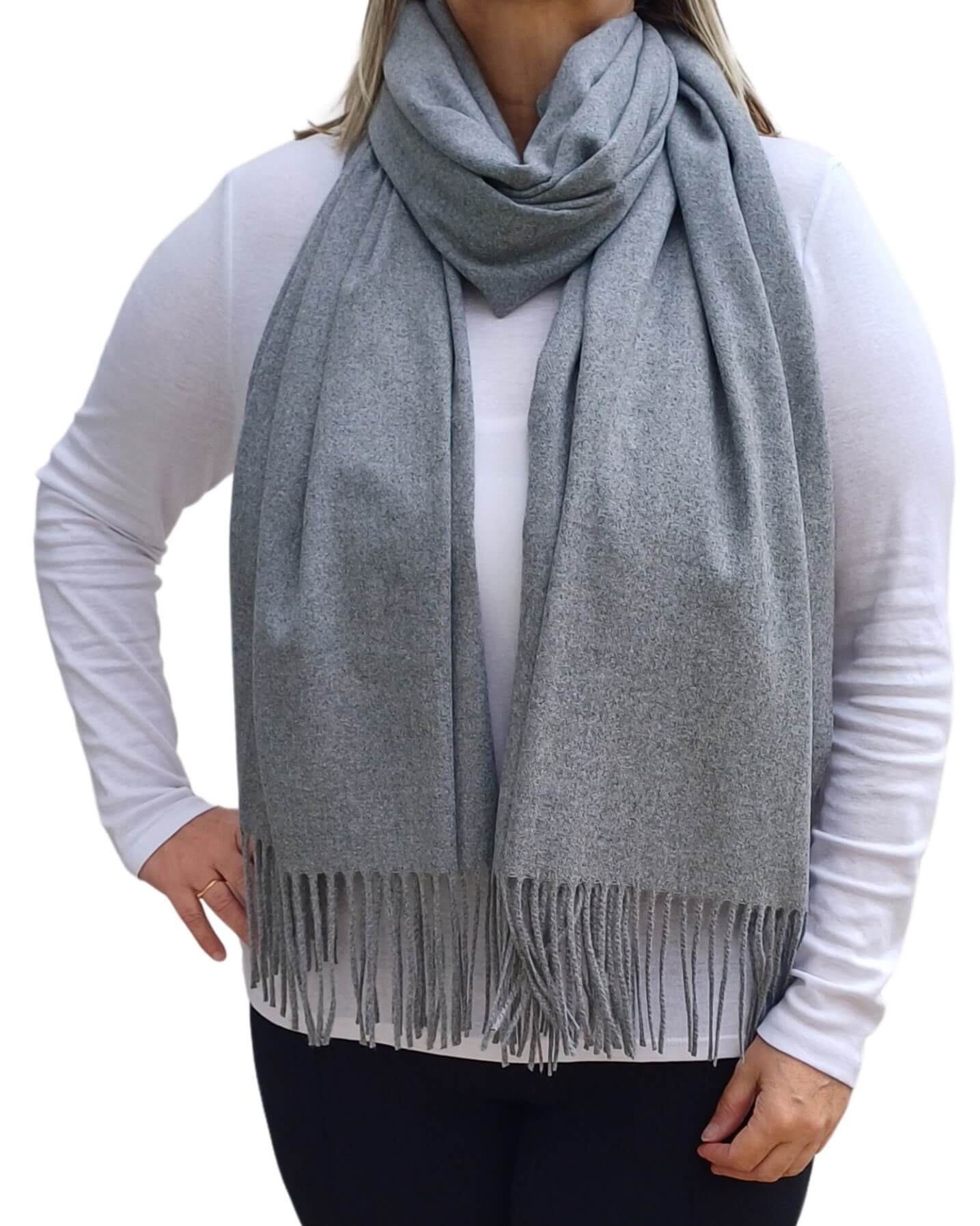 Aurora's Array: Woman models a soft, warm grey wool blend scarf with fringed edges, draped around her neck and shoulders.
