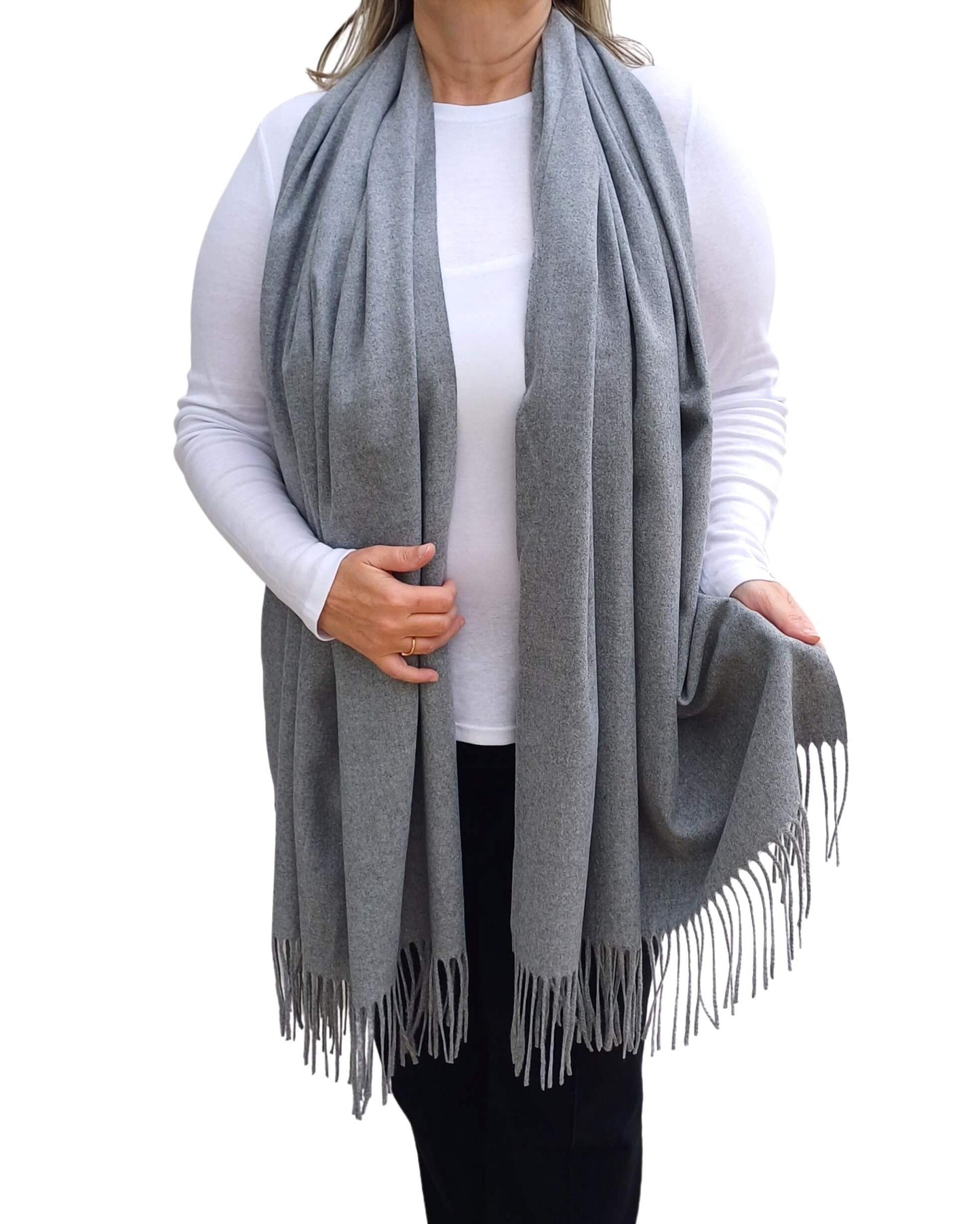 Aurora's Array: Woman models a soft, warm grey wool blend scarf with fringed edges, draped around her neck and shoulders.
