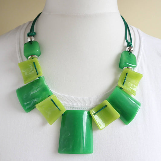 Chunky statement necklace with glossy green and lime rectangular and square beads. Strung on a dark green cord with silver accents.