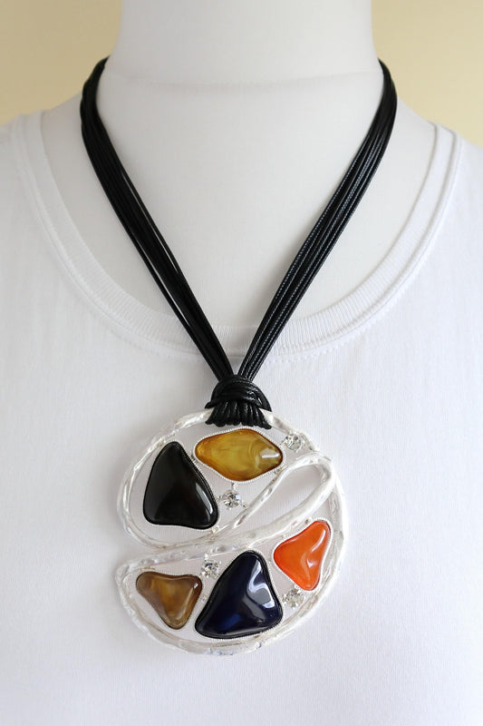 Unique geometric pendant necklace with black cords. Features colourful resin pieces in a silver-tone abstract setting. Bold and eye-catching jewellery.
