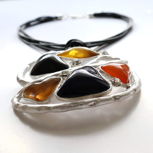 Abstract pendant necklace with black cords. Features colourful resin accents in a textured silver-tone geometric setting. Unique statement jewellery.