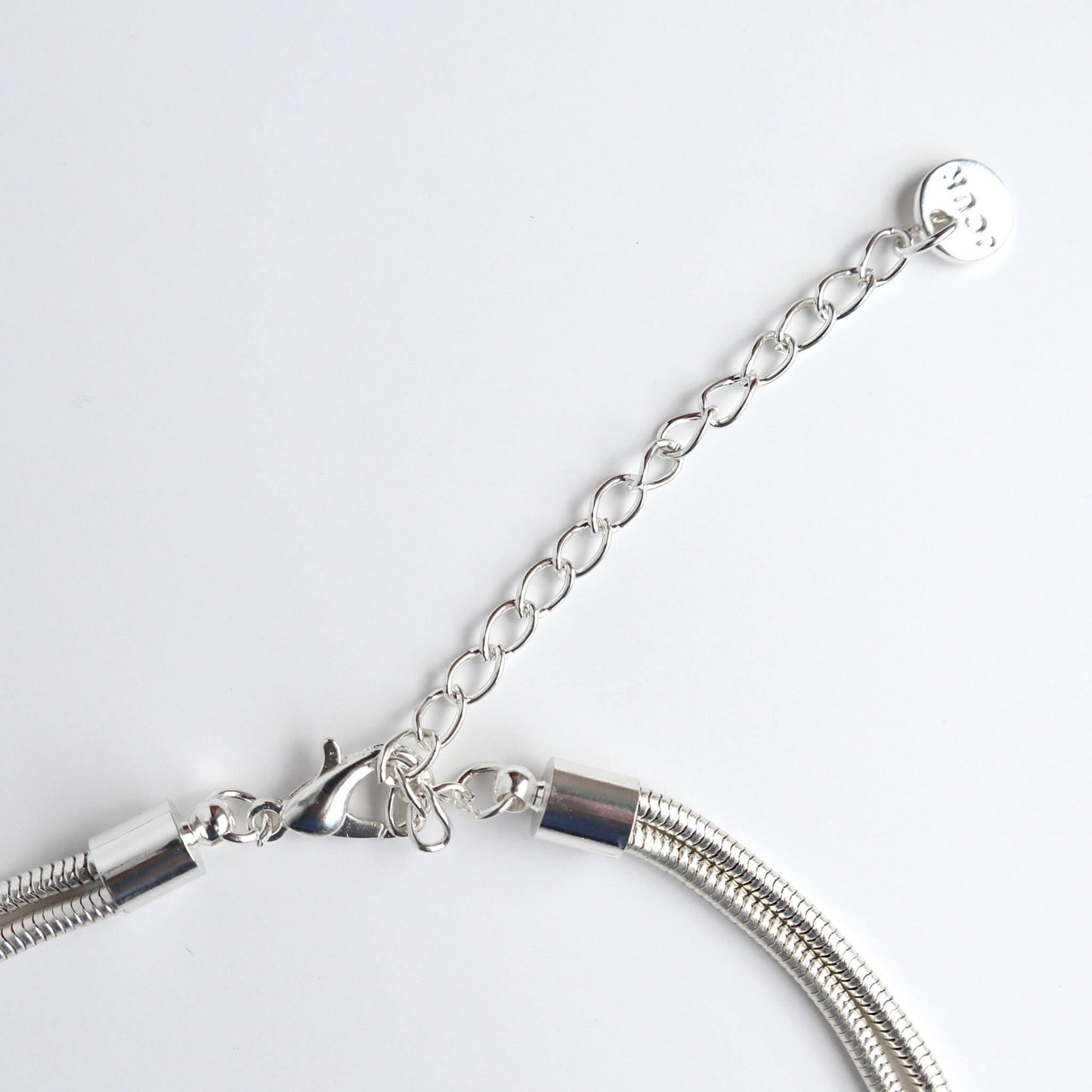 Close-up of a silver-toned necklace clasp, extender chain, and the ends of the multi-strand snake chain. Lobster claw closure.