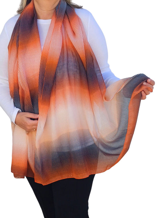 Lightweight scarf with flowing stripes in an ombre effect of orange, cream, and dark grey. Features a soft, textured feel.