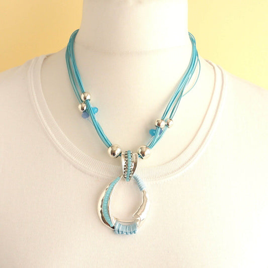 Teal cord necklace with a silver abstract oval pendant featuring embedded clear and teal crystals and wrapped teal thread.