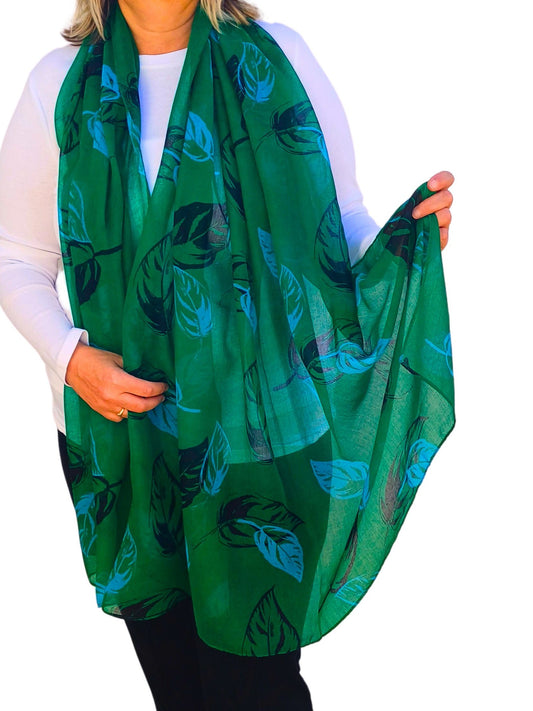 Aurora's Array: Woman models a soft, lightweight oversized green scarf with a large leaf print in shades of blue and black.