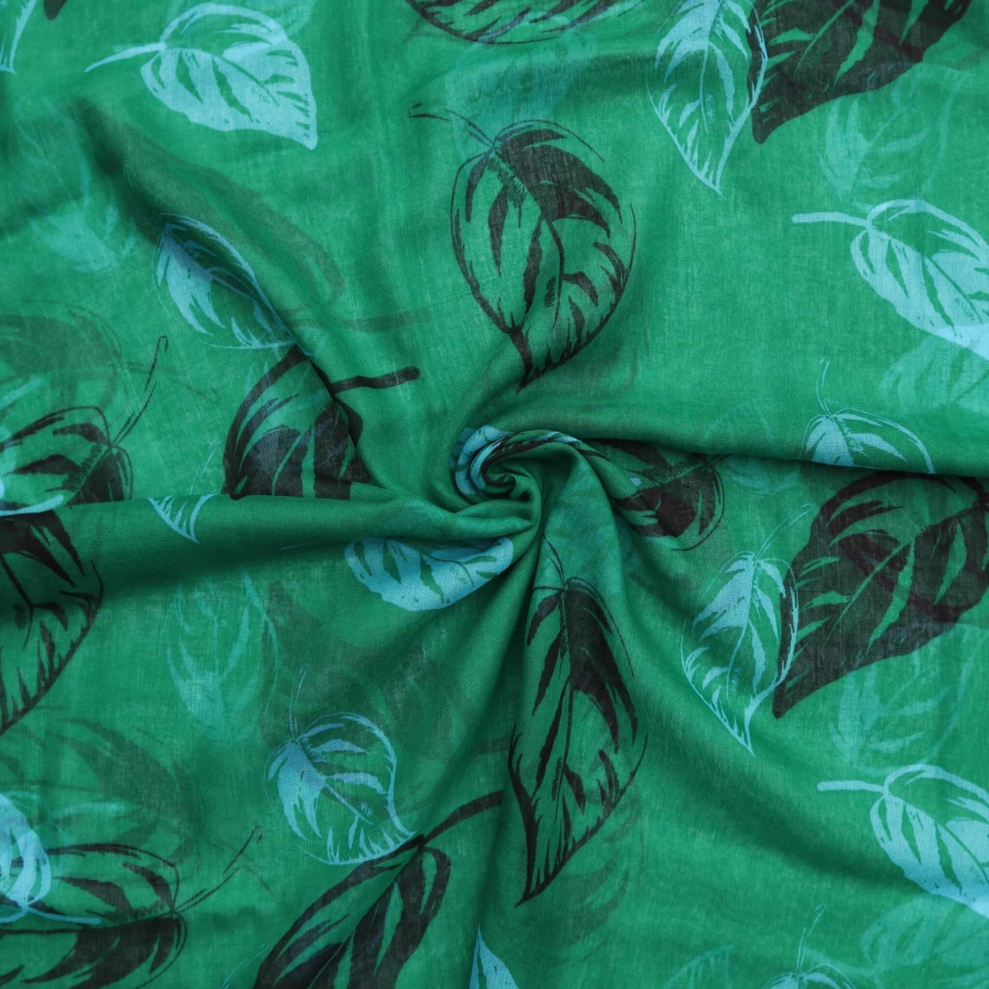 Aurora's Array: Close-up of a soft, lightweight green scarf with a large leaf print in shades of blue and black, swirled to show detail.