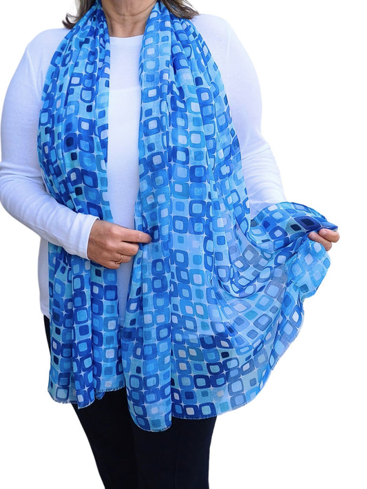 Lightweight summer scarf with a vibrant geometric square design in shades of blue and white. Stylish and airy accessory.