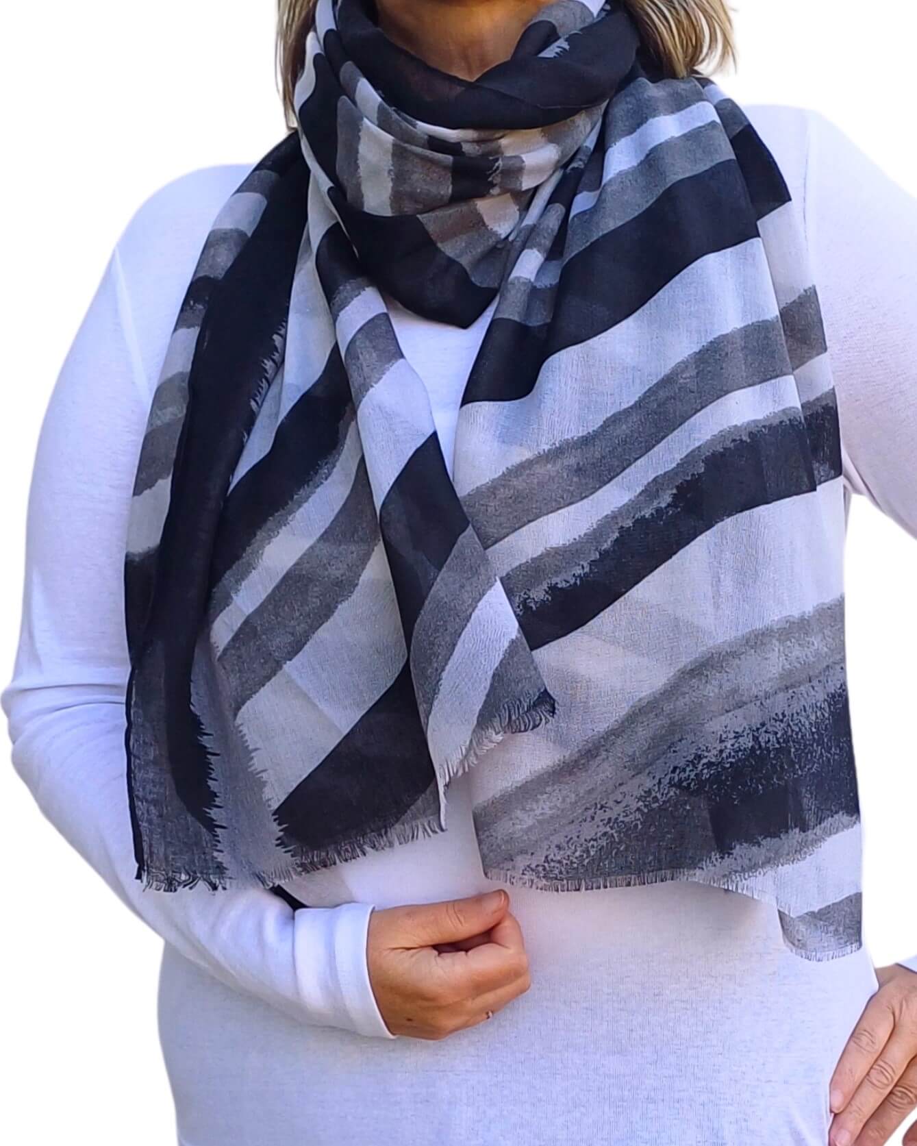Aurora's Array: Woman models a soft, lightweight scarf with blended horizontal stripes in black, grey, and white, wrapped around her neck.