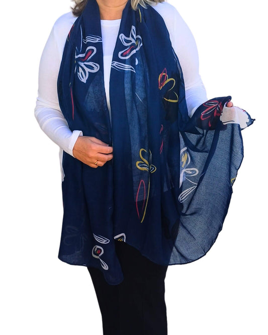Aurora's Array: Stylish lightweight oversized scarf featuring an abstract floral design in navy blue, white, yellow, and pink, worn draped by a woman.