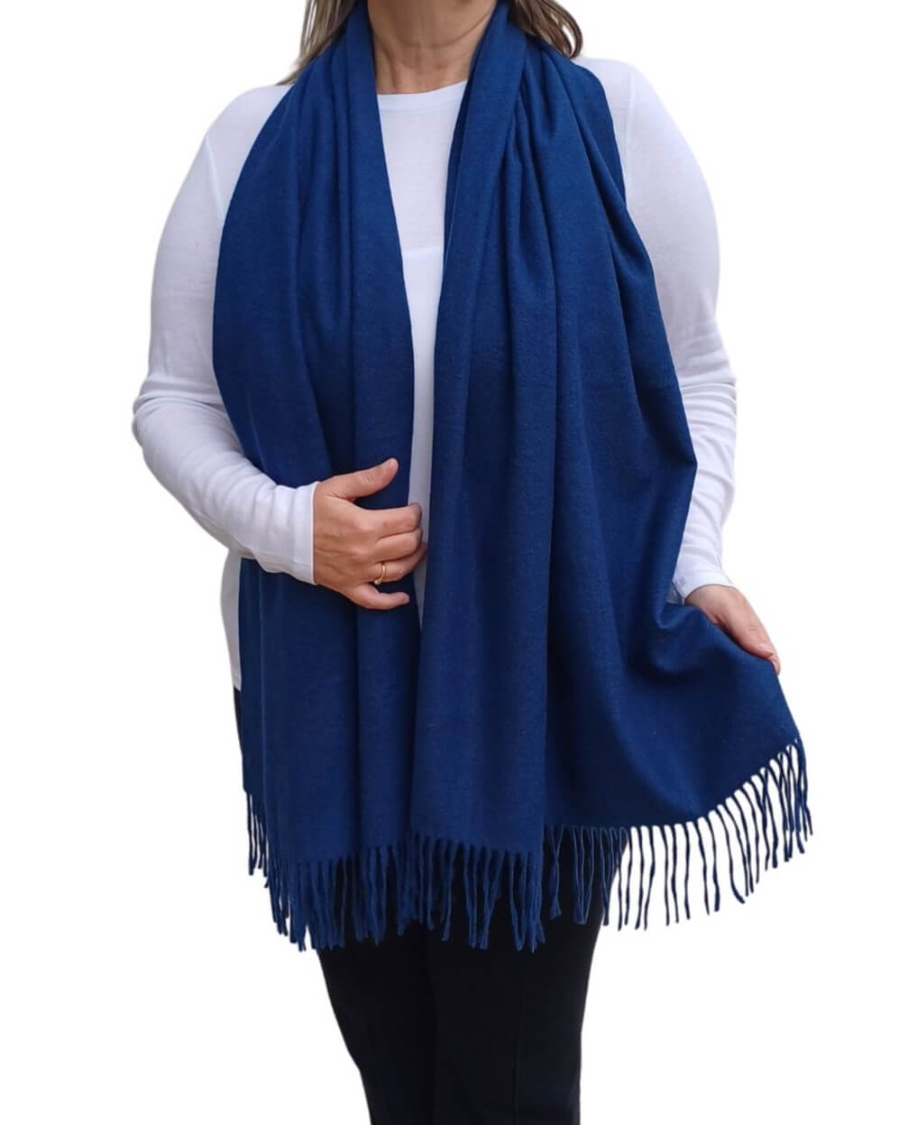 Aurora's Array: Woman models a soft, warm navy blue wool blend scarf with fringed edges, draped around her neck and shoulders.