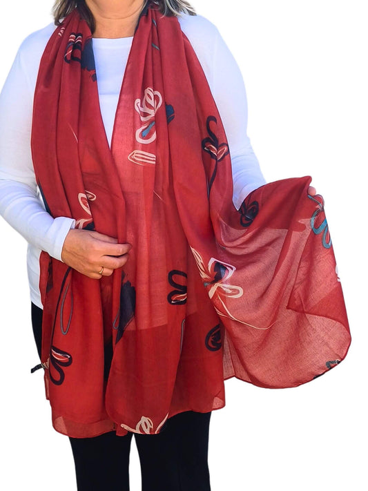 Aurora's Array: Woman models a soft, lightweight oversized scarf with an abstract floral print in shades of red, white, and blue.