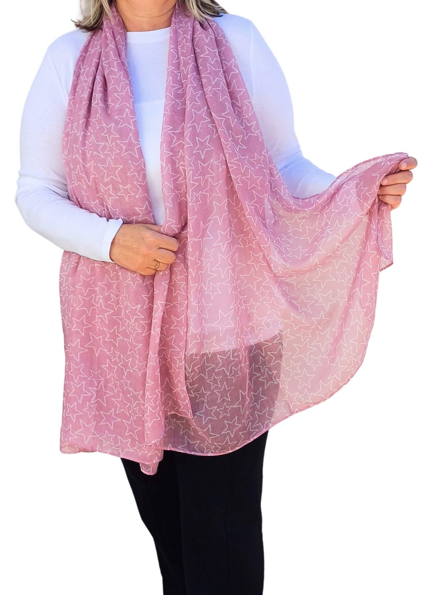 Aurora's Array: Woman models a soft, lightweight dusky pink scarf with a subtle white star print.