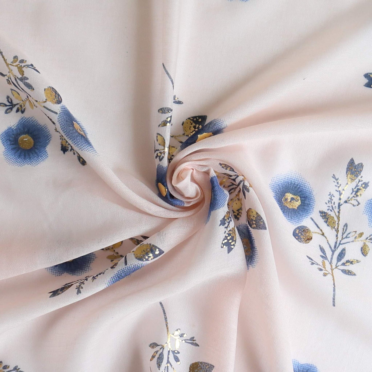 Aurora's Array: Close-up of a soft, lightweight pale pink scarf with a small blue and gold floral print, swirled to show detail.