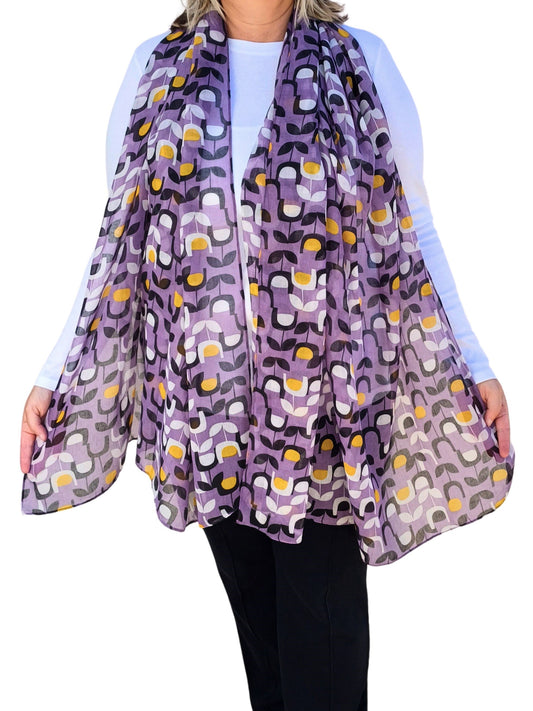 Aurora's Array: Woman models a soft, lightweight oversized scarf with a retro floral print in shades of purple, black, white, and yellow.
