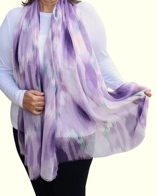 Soft purple scarf with an abstract ikat-style design in shades of lavender, white, and a hint of teal. Lightweight, flowing fabric.