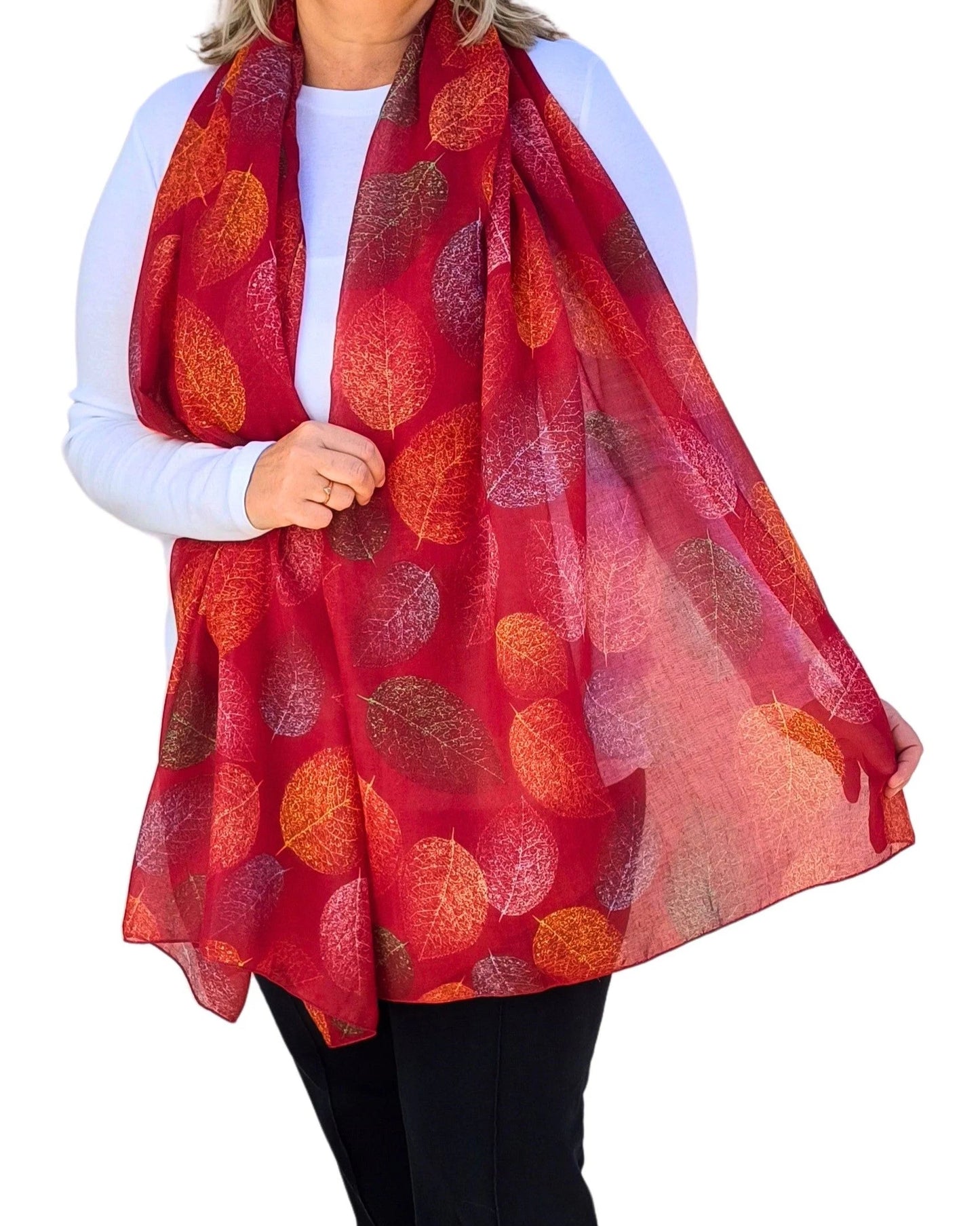 Lightweight red oversized scarf with autumn leaf pattern, modelled on white background