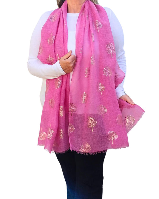 Aurora's Array: Woman models a soft, bright pink scarf with a subtle rose gold tree print and frayed edges.