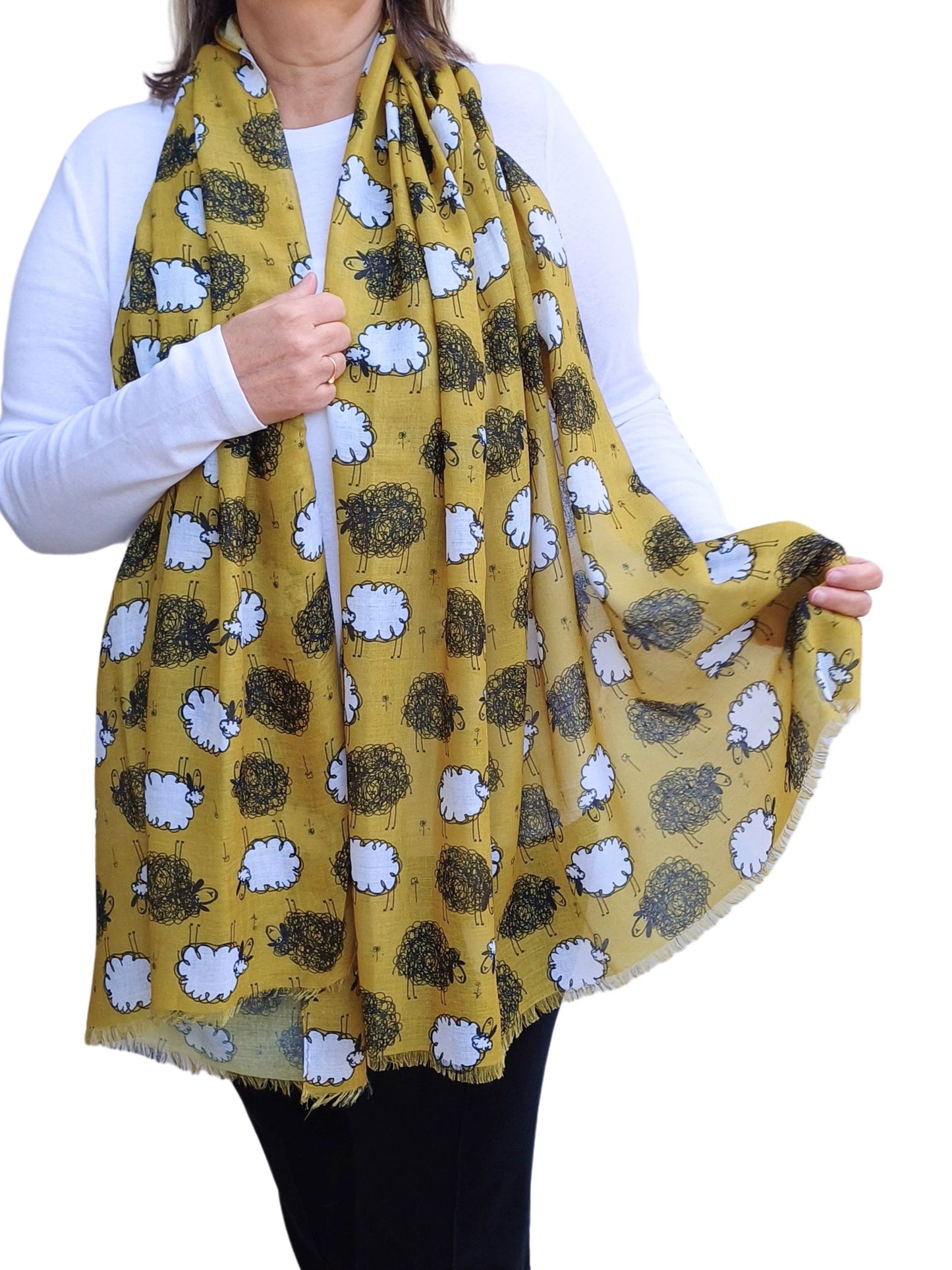 Mustard yellow scarf adorned with charming black and white sheep illustrations. Lightweight, draped fabric with a subtle fringe detail.