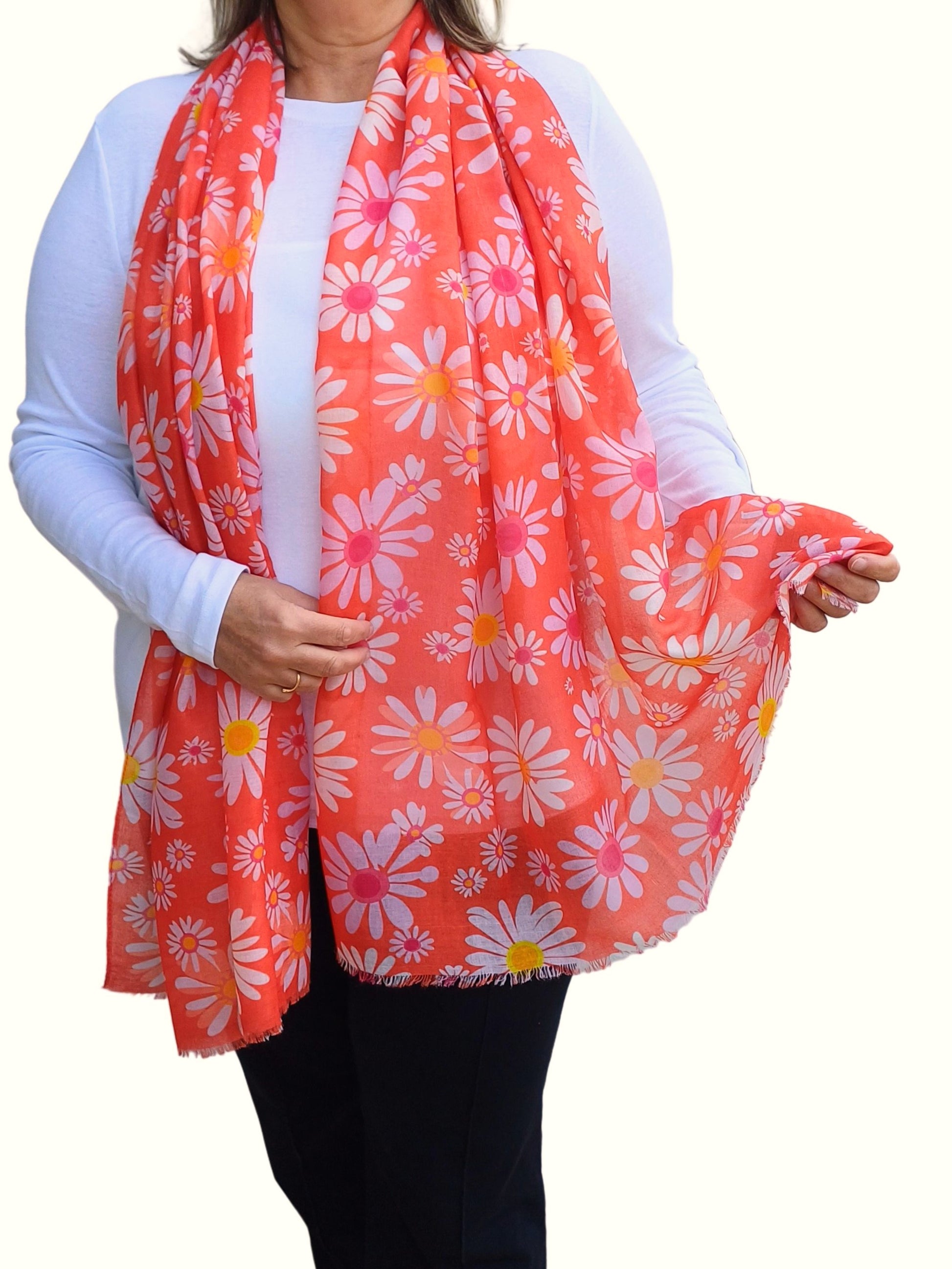 Vibrant orange scarf featuring a playful print of white and pink daisies with yellow centers. Lightweight and soft to the touch.