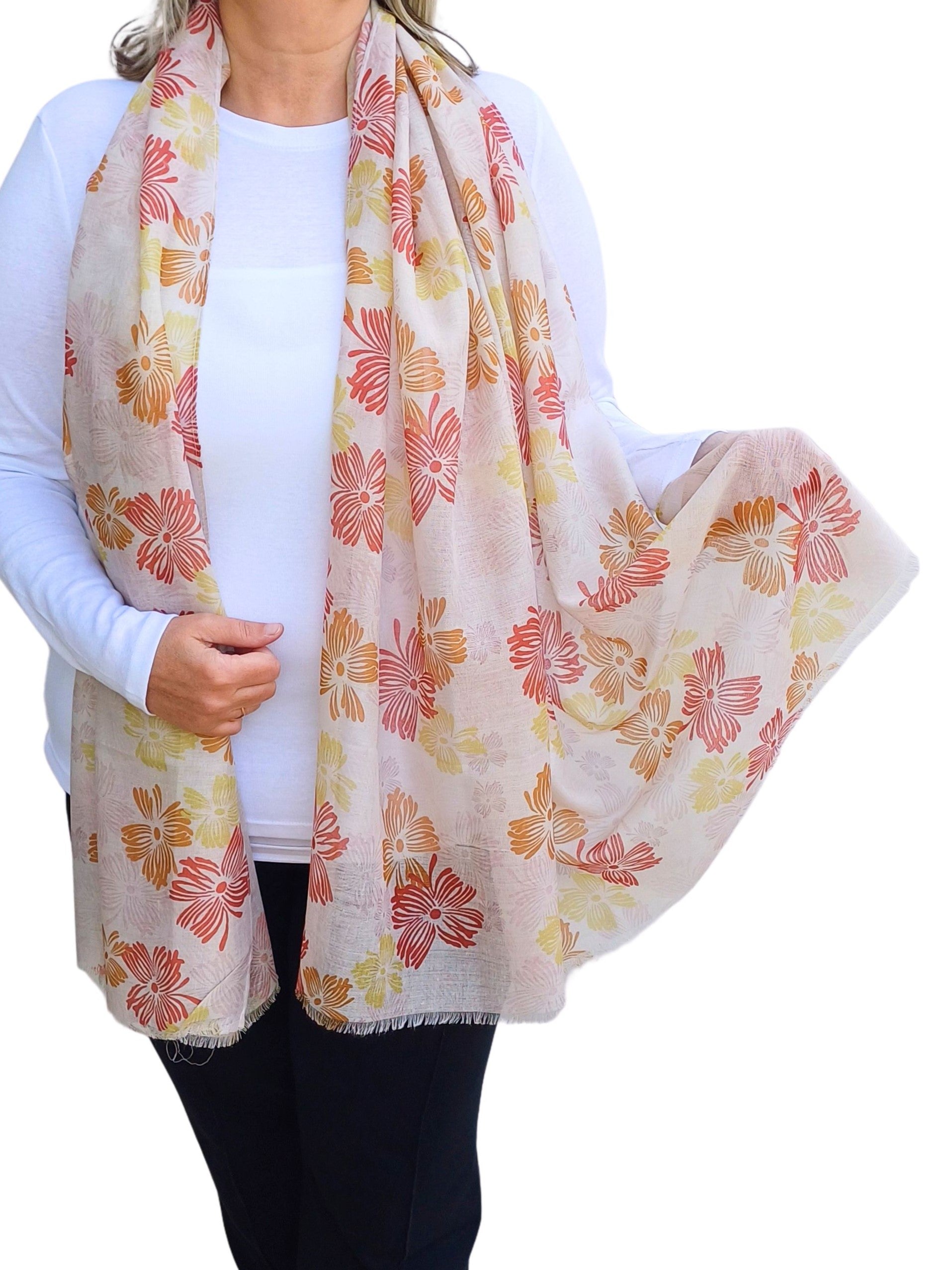 Aurora's Array: Woman models a lightweight pale pink scarf with a floral print in shades of red, orange, and yellow.