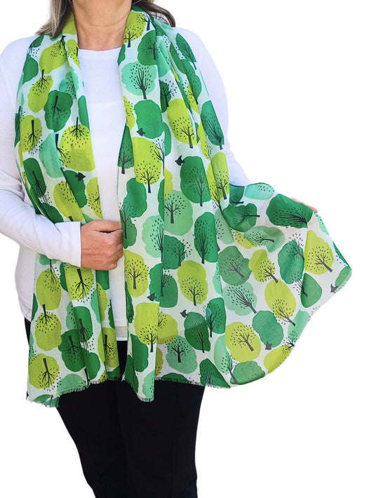 White scarf with an abstract tree print in various shades of green. Lightweight, flowing fabric with subtly fringed ends.