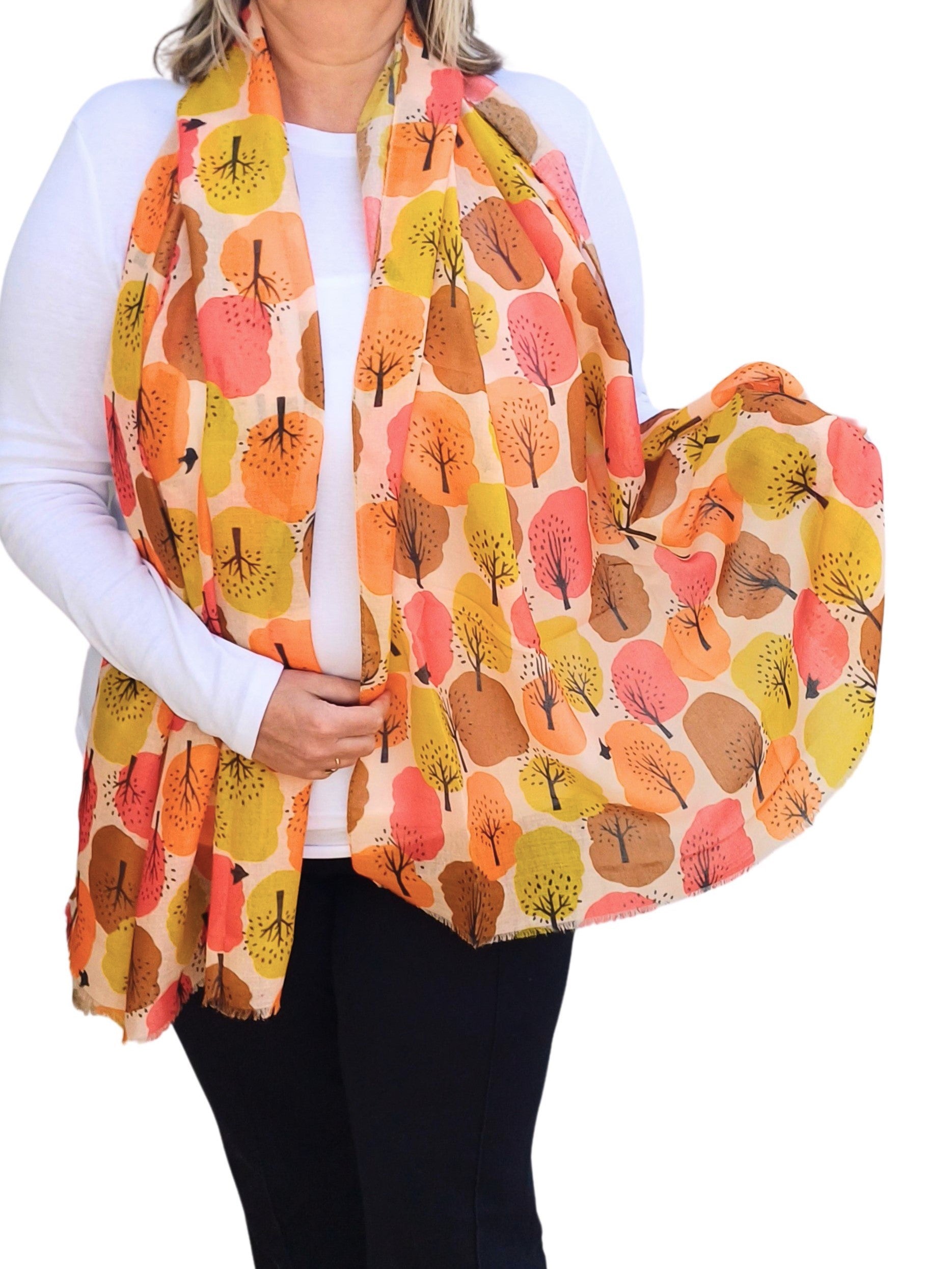 Creamy scarf with an abstract tree pattern in shades of orange, yellow, brown, and pink. Lightweight, flowing fabric with subtly fringed ends.