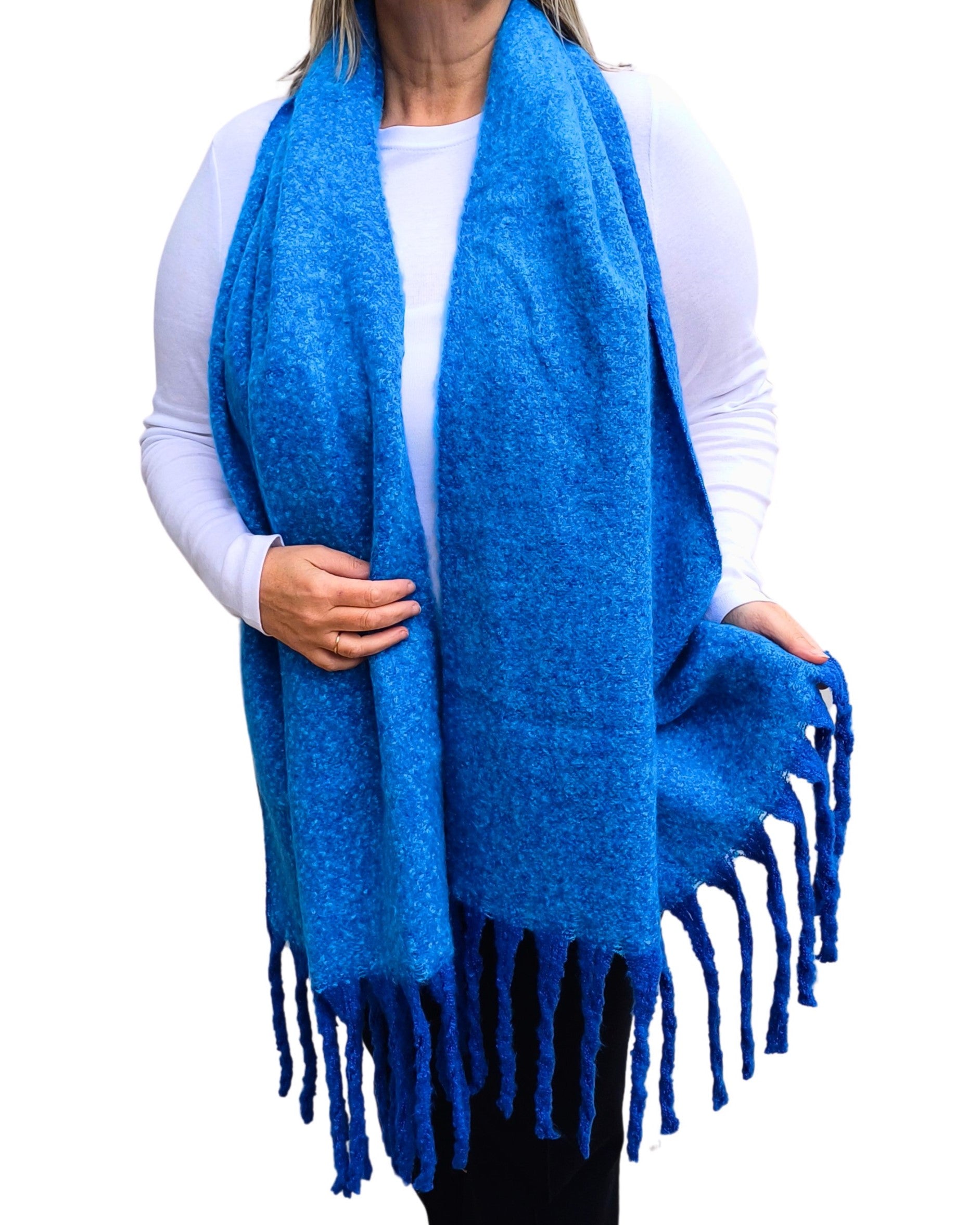 Aurora's Array: Woman models a soft, textured bright blue knit scarf with long fringe.