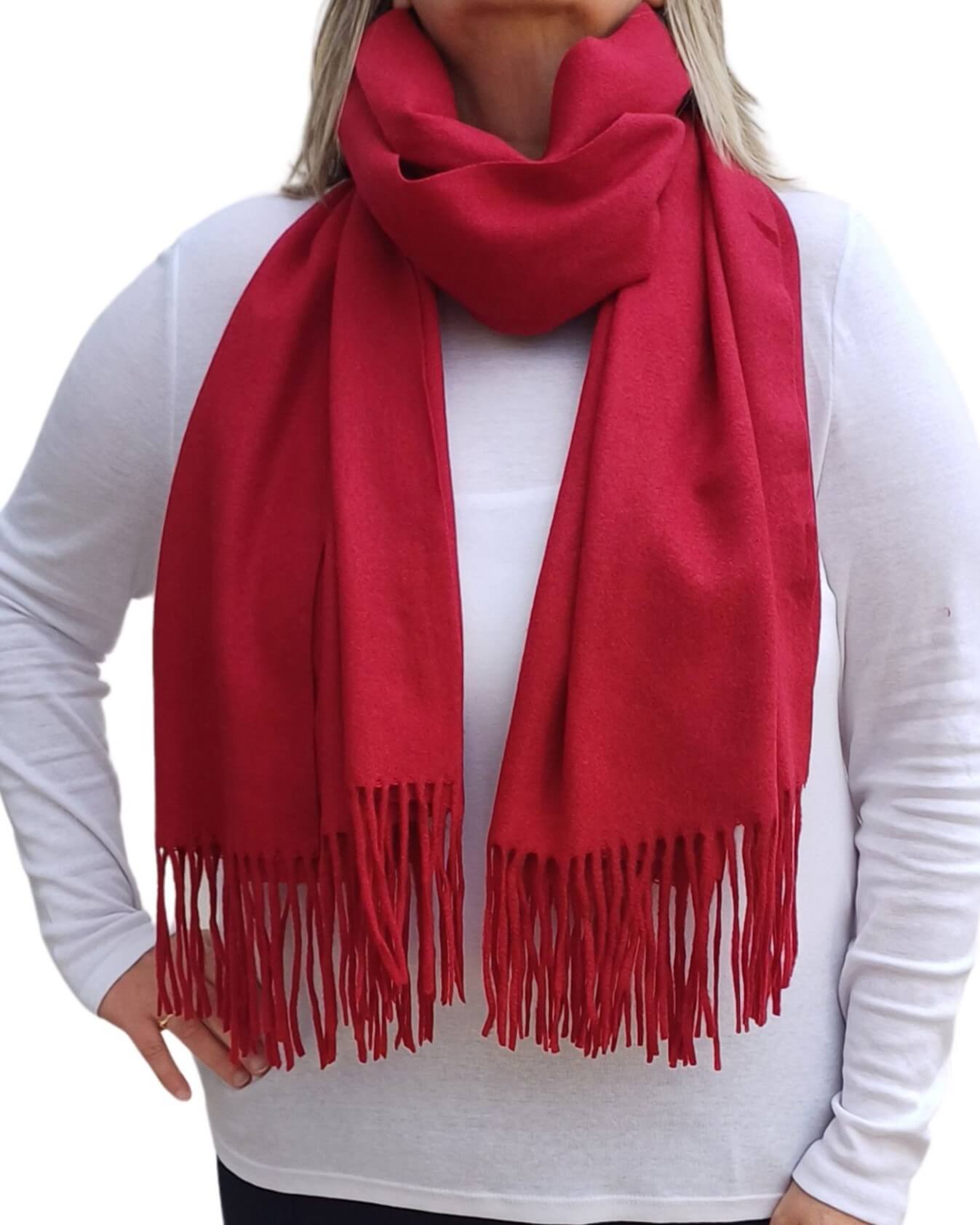 Aurora's Array: Woman models a soft, warm wine red, crimson wool blend scarf with fringed edges, draped around her neck and shoulders.